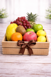 Fresh fruit gift crate with pineapple, red grapes, apples, kiwi, oranges, lemons and papaya presented in a wooden gift crate in the Philippines
